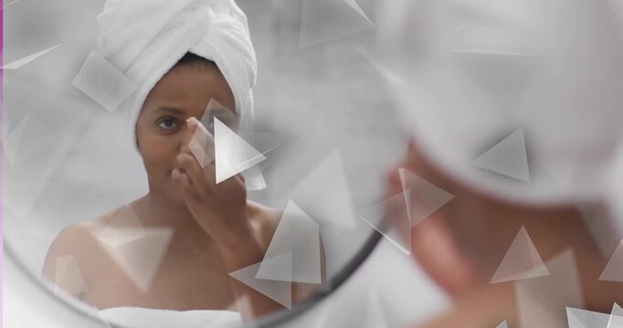 Woman checking mirror doing skincare, dabbing cream while triangle overlays crossing reflection