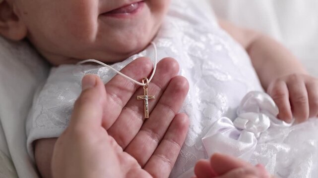 Sacrament of baptism. Woman putting gold cross on little baby indoors, closeup