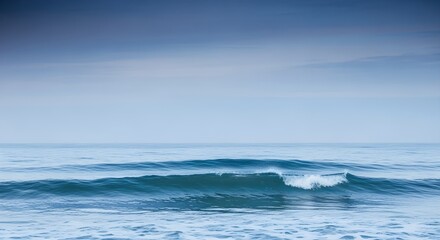 Fototapeta premium A tranquil oceanic vista, capturing a single cresting wave in atmospheric blue tones, creating a soft, reflective, and subtly cinematic mood across the serene water