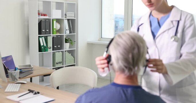 Hearing test. Doctor adjusting patient's audiometric headphones in clinic