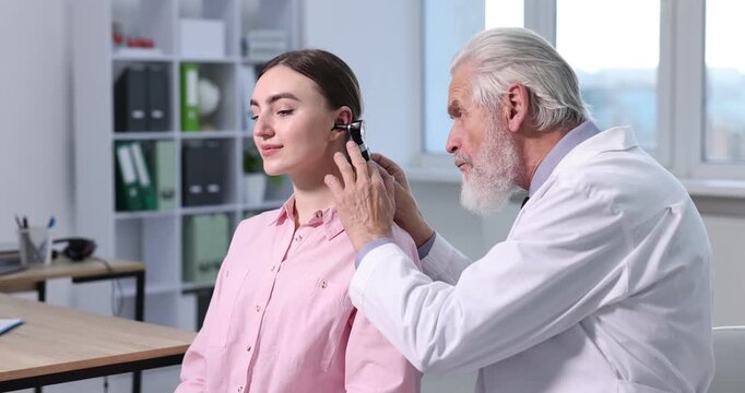 Hearing test. Doctor examining patient&rsquo;s ear with otoscope in clinic