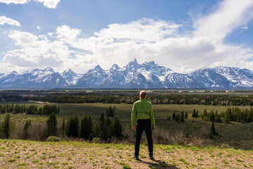 The visitor enjoys a peaceful moment with the iconic Tetons rising above the valley, Early spring travel in Wyoming, USA