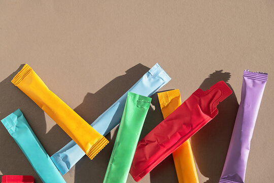 Variety of colorful powder sachets on neutral background with copy space.