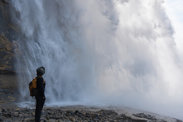 Obraz premium A hiker marvels at the grand, misty waterfall. The power of nature visible.