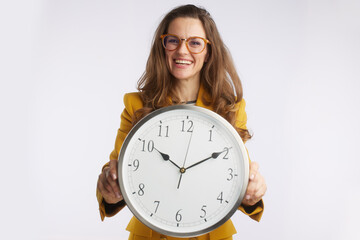 A confident businesswoman wearing glasses holds a large analog clock, representing precision, awareness of deadlines, and effective time management in the corporate world.