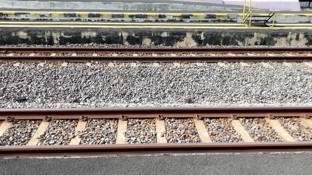 A ground-level view of train tracks running parallel to a station platform