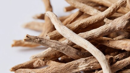 Dried, tan-colored, thin roots or plant stems piled up against a white background
