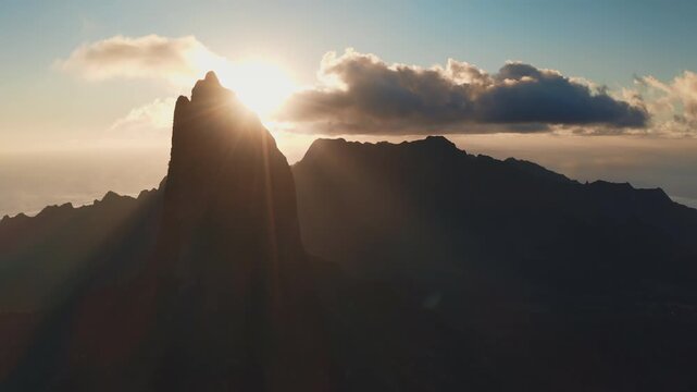 Moorea island majestic mountain peaks emerging from the dark silhouette as golden sunbeams radiate across the sky, highlighting the tranquil tropical landscape and inspiring a sense of calm