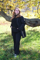 Portrait of a young woman in sunny autumn park	