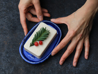 Woman's Hands Holding Handmade Blue Ceramic Soap Dish with Natural Soap, Pine Needle and Red Berries &ndash; Christmas Spa Mood. organic lifestyle blogs and premium interior styling. cobalt blue glaze