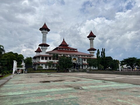 Grand Mosque of Cianjur, West Java, Indonesia, featuring distinctive architecture, twin minarets, and reflective courtyard pool under a cloudy sky. - Powered by Adobe