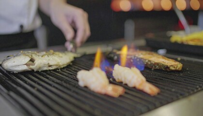 Chef grilling seafood with flames.