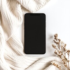 A sleek smartphone rests atop a vibrant bouquet of colorful flowers, nestled among soft, cozy blankets, creating a warm and inviting atmosphere.