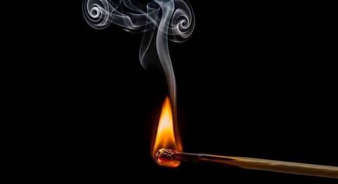 Close up of a burning matchstick with swirling smoke on black background for conceptual design