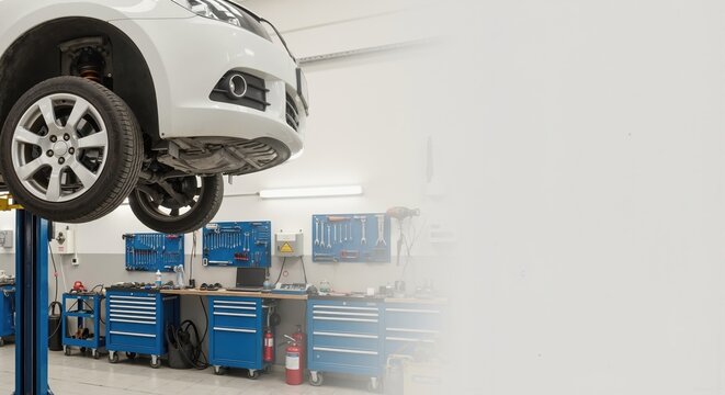 Car on a hydraulic lift at an auto service station. Vehicle maintenance and repair in a modern workshop with copy space for text