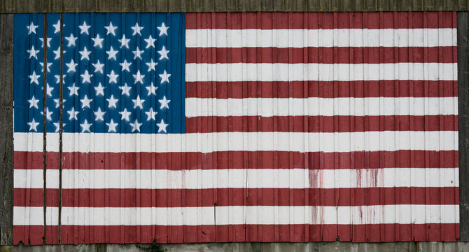 Red, white, and blue American flag painted on a rustic old wood barn, stars and stripes patriotic symbol of the USA, July 4th, Memorial Day, Veteran’s Day, Independence Day