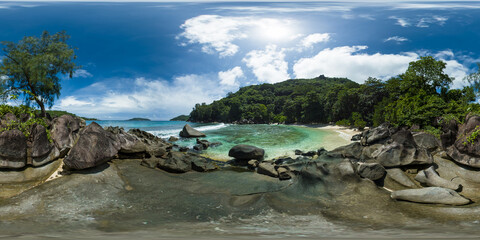 A stunning beach framed by rocky outcrops and lush forest, with turquoise waters gently lapping the shoreline. Mahe, Seychelles. 360 panorama VR.