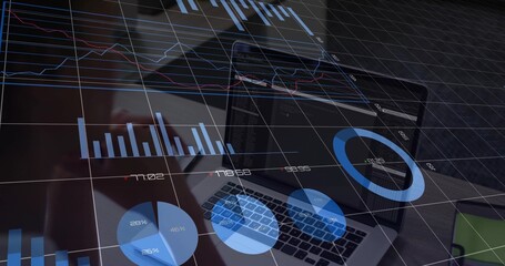 Displaying centered laptop showing blue charts at office desk, with keyboard, phone, green notebook