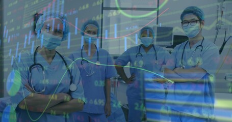 Posing medical team wearing blue scrubs and masks in clinic, showing stethoscopes, stock tickers