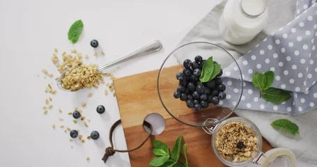 Fototapete Aroma Displaying glass bowl of blueberries with mint sprig on wooden cutting board, with granola  © vectorfusionart