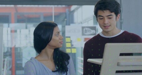 Viewing team in maroon sweater and light blue blouse studying monitor with sticky notes in office