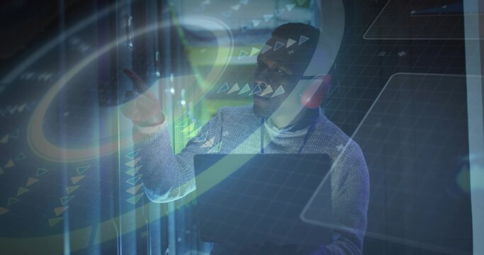 Using holographic UI, man in sweater over collared shirt, AR headset and tablet near server racks