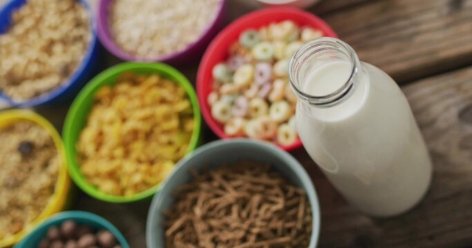 Displaying clear glass milk bottle with open neck on wood table, featuring cereal bowls, copy space