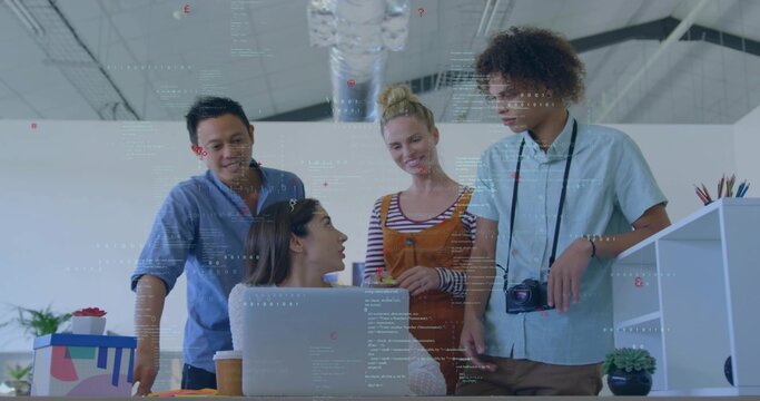 Collaborating team leaning over laptop in studio, with DSLR camera, coffee cup, wearing overalls