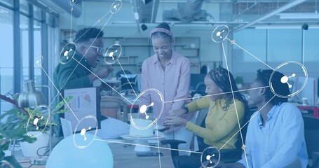 Gathering four colleagues wearing business attire around small cake at desk with digital overlay