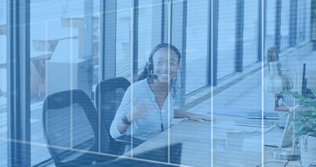Smiling woman in blouse wearing headset answering calls at office desk, glass binary overlay