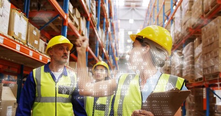 Pointing female lead directing team in warehouse aisle with clipboard, hardhat, hi-vis vest, HUD