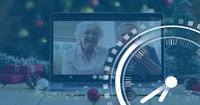 Displaying laptop screen showing senior couple chatting at home living room, with gifts, ornaments