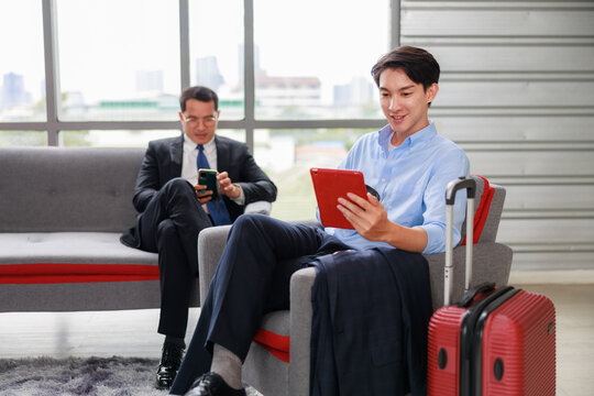 asian businessman relaxing on a lounge sofa with coffee and a digital tablet in a modern office setting, taking a break while reviewing work updates and enjoying a calm moment in a contemporary corpor