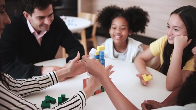 Group of multiracial students and teachers playing fun mathematical puzzle game on tables together, creatively learning in primary class, kids challenge for wisdom at elementary international school.
