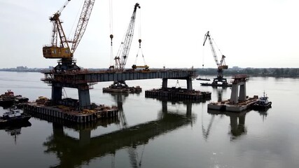 Bridge Construction Site with Cranes and Barges on Water.