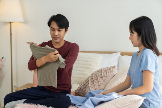 Man lifestyle casual clothing choice in bedroom with woman sitting on bed