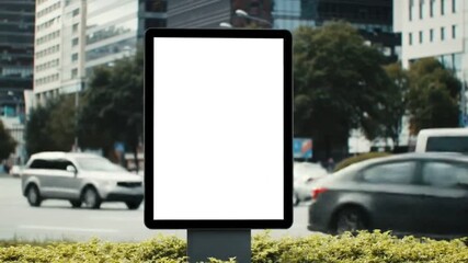 Blank white vertical street billboard display template in a bustling urban environment with motion-blurred cars on a busy road, ideal for advertising and marketing campaigns