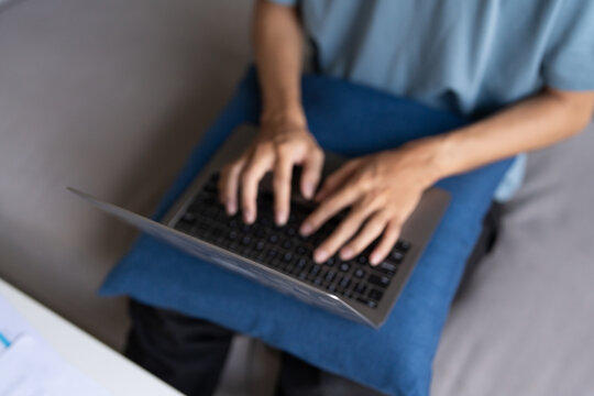 Asian Man Working from Home on Laptop with Technology Concept, Sitting on Sofa for Online Business and Remote Work Meeting