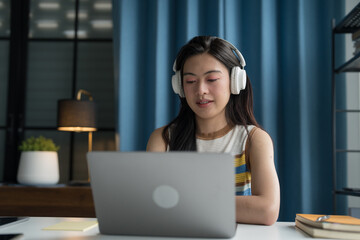 Online Tutoring Asian Girl in Headphones Engaged in Online Class with Laptop education writing homework study e-learning preparing for exam