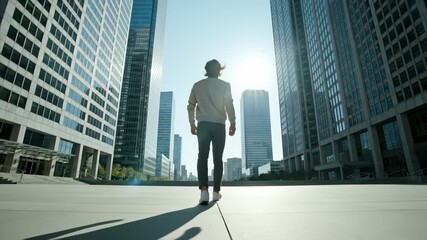 Man Walking in Downtown City Center Between Skyscrapers in Bright Sunlight