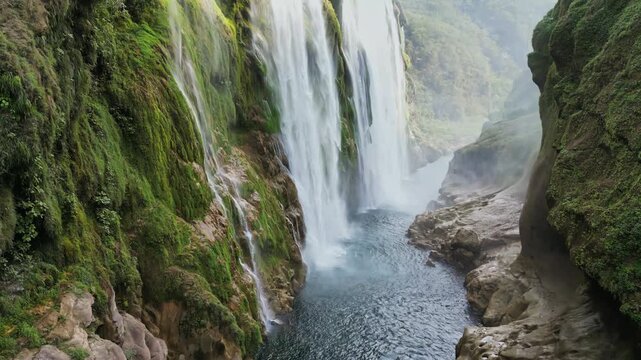 Aerial drone view of Tamul Waterfall cascading down green cliffs into a turquoise pool below