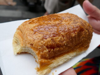 Golden brown baked delicious croissant held up on napkin
