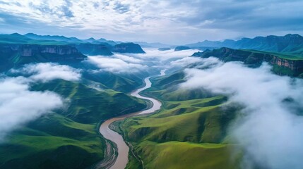 Aerial View of Serpentine River Flowing Through Lush Green Mountains and Misty Clouds
