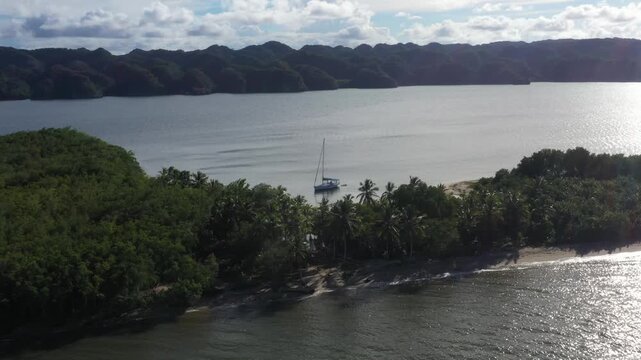 4k 24fps droni in the caribbean beach with mountains behind and the sailboat in the water