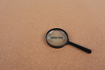 Magnifying glass placed on a cork board background. Idea for searching, detective work or typing text