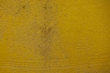 close-up shot of a textured gold yellow concrete surface. The rough and slightly uneven texture,...