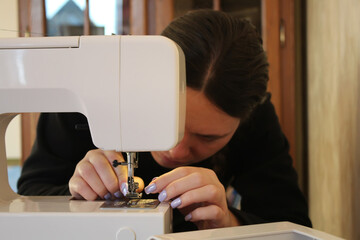 A woman at home, going about her daily business. Working with a sewing machine, hemming clothes. A woman sewing.