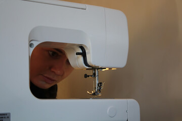 A woman at home, going about her daily business. Working with a sewing machine, hemming clothes. The woman examines a broken needle.