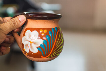 Hand holding traditional Mexican barro potter mug