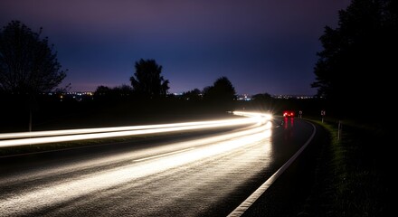 Nighttime road with light trails from cars, illuminated highway, and urban scene in the dark